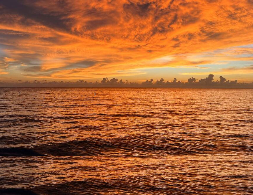 La vasta extensión del océano al atardecer, con nubes de color naranja y rojo intenso que se reflejan en la superficie del agua, ilustra las temperaturas récord del mar en el Pacífico tropical. (Foto: OMM/Matthew Wilson)